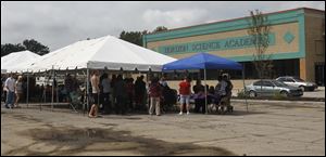 Students of Horizon Science Academy attend orientation under two tents in the parking lot of DeVeaux Village on Tuesday. The City of Toledo denied an occupancy permit to the building last week. 