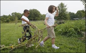 Donovan Williams, left, and Riley Hurst, both 6-year-old first graders at Grove Patterson Academy in Toledo, carry a a vine from a squash plant to a compost pile during the school's annual garden celebration.