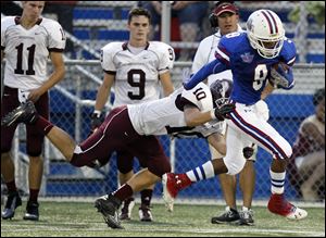 Springfield's JeSean Fisher makes a catch for a first down as Rossford's Sean McCormick makes the tackle in Friday night's game.