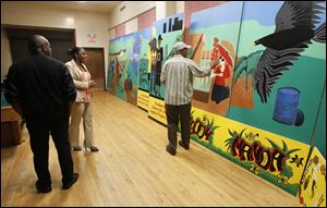 At the Frederick Douglass center, Warren Woodberry, right, shows the mural he helped design. It was painted mostly by residents of the Moody Manor apartments, where gunfire killed a girl, 1, and injured her sister, 2. The mural is to be installed at Moody Manor.