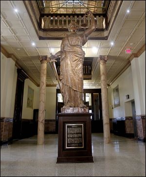 A 13-foot copper statue of Lady Justice that once stood atop the sandstone clock tower watches over those passing through the foyer of the Auglaize County Courthouse.