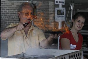 John Skiadas makes saganaki flaming cheese. The festival remains in full swing today from noon to 7 p.m.