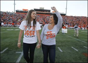 Bowling Green State University students Kayla Somoles, left, and Angelica Mormile, are cheered as they take the field as honorary captains participating in the coin toss before the Idaho football game at Doyt Perry Stadium on Saturday. The pair were severely injured in a wrong-way crash on I-75 on March 2 that killed their sorority sisters Christina Goyett, Sarah Hammond and Rebekah Blakkolb as well as the wrong-way car's driver.