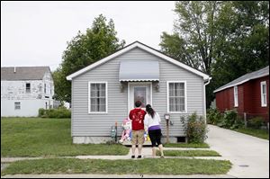Friends Carrie Greenman, right, and David, (who did not want to use his last name), left, stand in front of the home of Heather Jackson, 23, who was found murdered in her home on John Street in Sandusky. Her 3-year-old daughter and 18-month-old son were also found dead at the scene.