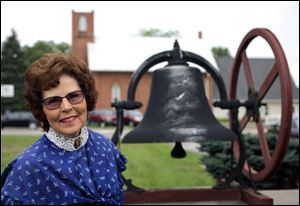 Trudy Urbani, past president of the Historical Society of Bedford, with the bell from First Wesleyan Methodist Church, says it is important to keep history alive for future generations.