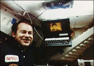 In this June 18, 1985, photo, astronaut John Creighton poses with the onboard Graphical Retrieval Information Display computer, which displays a likeness of the character Mr. Spock from Star Trek. Bill Moggridge, who designed the GRID computer, an early portable with a flip-open shape that is common today, died. He was 69.