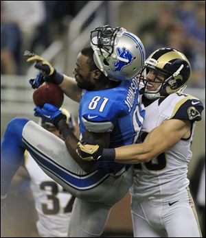 Lions receiver Calvin Johnson loses his helmet after being tackled by St Louis' Craig Dahl. Johnson had 111 yards receiving.