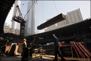 An ironworker watches as a crane lifts a load of construction supplies at the World Trade Center transportation hub recently in New York. More than a year after bringing a 17 1/2-foot box beam from the wreckage of the World Trade Center to Tiffin, the city's 911 Memorial Committee on Sunday dedicated a permanent memorial with the beam at its center.