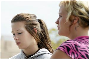 Karlee Tomek, 17, a cousin of Heather Jackson, and Amanda Thoren, a friend of the victim, react to the memorial outside the house.