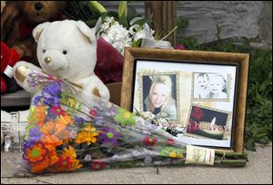 A picture of Heather Jackson, 23, and her two children, Celina Jackson and Wayne Jackson, is nestled among a growing memorial of flowers and stuffed animals outside the home where they were found slain in Sandusky.