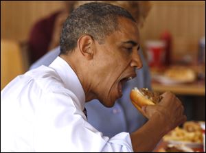 President Barack Obama takes a bite out of a chili dog during an unannounced visit to Rudy's Hot Dog in Toledo.