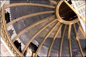 The stained-glass dome in the courthouse's main courtroom was covered by a suspended ceiling in the 1950s. In the process, holes were crudely punched for duct work and wiring to hold the ceiling.