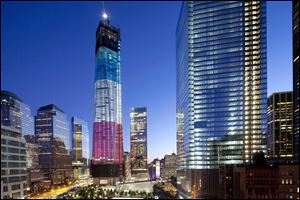 The tower known as 1 World Trade Center, left, the National September 11 Memorial, bottom left, and 4 World Trade Center, right, are bathed in light, Tuesday, in New York. 
