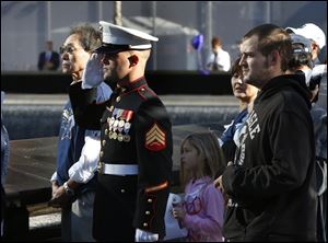 A US Marine salutes as he and others stand at the north reflecting pool of the World Trade Center Memorial during a moment of silence.