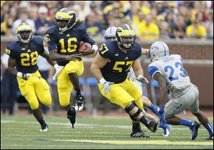 University of Michigan quarterback Denard Robinson, 16, gets a block from teammate Elliott Mealer, 57, as Robinson cuts inside against Air Force during the third quarter at the Big House in Ann Arbor, Air Force defender is Steffon Batts (23) Saturday, September 8.