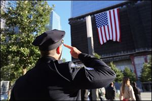 A New York City Police officer salutes a flag hanging from the One World Trade Center building, during ceremonies for the 11th anniversary of the attacks at the World Trade Center, in New York.