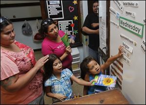 Adriana Borjas, left, stands next to her daughter Reina Conejo, 7, Felicia Guel, center, and her daughter Mya, 6, as they participate in the open house at the Queen of Apostles School in Toledo.