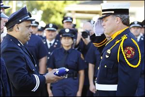Fire Station 6 Captain Dave Rodriguez, left, accepts the station flag from Private Jeff Koenigseker, commander of the Toledo Fire Department Honor Guard, during a 9/11 Commemoration Ceremony and Dedication of Fire Station 6 at 1155 Oak Street, Tuesday.