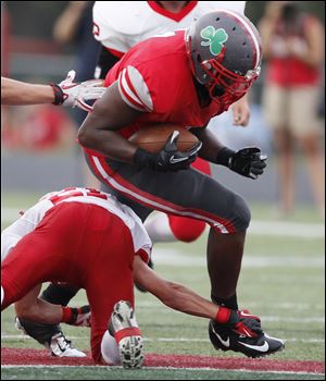 Toledo Central Catholic player Keith Towbridge looks to elude Bedford High School defenders at Gallagher Stadium in Toledo earlier this year.