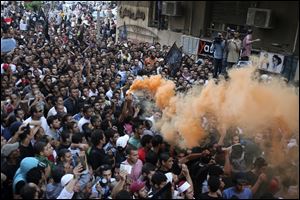 Protesters chant slogans amid orange smoke outside the U.S. embassy in Cairo, Egypt.