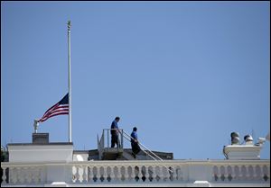 White House workers walk on the roof of the White House after lowering the flag to half staff Wednesday for the death of U.S. ambassador to Libya Christopher Stevens.