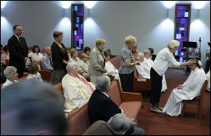 Participants in the ordination of Beverly Bingle, seated, line up for the laying on of hands at the First Unitarian Church. Thursday's ceremony was conducted by Roman Catholic Womenpriests.