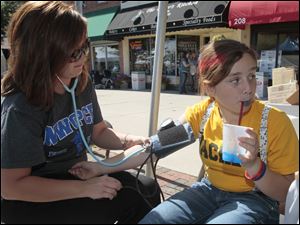 Northwest Ohio Primary Care Physicians [NWOPCP] Melinda Gosche, of Kansas, left, taking the blood pressure of Gabriella Benington, 11, of Perrysburg as part of a free service at the NWOPCP table.