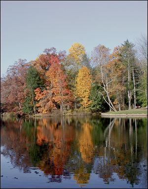 Brilliant fall leaves are reflected on the waters of Mallard Lake at Oak Openings Preserve Metropark.