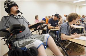 Kyle Cannon,18, listens in class while his health aid, Dan Dorner, center in baseball cap, takes notes for him at Bowling Green State University. Canon was a Clay freshman when he was paralyzed during a hockey game in 2008.