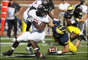 Massachusetts' Michael Cox loses the ball as Michigan's Craig Roh closes. Cox played three seasons for Michigan. He had 76 rushing for the Minutemen on Saturday.