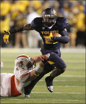 Toledo running back David Fluellan carries the ball as Bowling Green defensive lineman Ted Ouellet holds on during the fourth quarter.