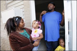 Jasmine Taylor holds daughter Kale-Jah Williams, 2, as Travis Williams speaks about the little girls' asthma proplems at apartment at Greenbelt Apartments. At right is the couple's other child, son Keontea Taylor, 2. The pair believe Kale-Jah's asthma problems are related to the cockroaches in their apartment.