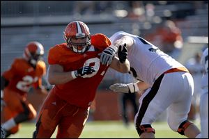 Chris Jones, left, pushes past offensive lineman Alex Huettel during a BGSU football scrimmage at Doyt Perry Stadium in August.