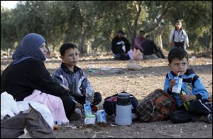 Newly-arrived Syrian refugee families rest after crossing the border from Tal Shehab in Syria, through the Al Yarmouk River valley, to Ramtha, Jordan, Saturday.