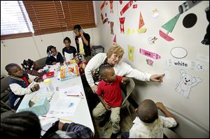 Volunteer Tami Rehklau talks with children about colors in the Moody Manor Reading Room in central Toledo.