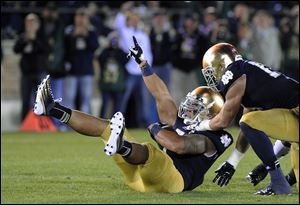 Notre Dame's Manti Te'o, left, reacts with Zeke Motta after Te'o makes an interception during the first half against Michigan Saturday in South Bend, Ind.
