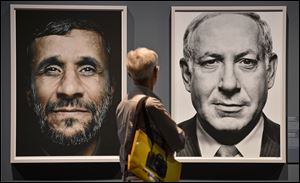 A visitor looks at  portraits of Iran's President Mahmoud Ahmadinejad left and Israel's Prime Minister Benjamin Netanyahu, during the exhibition Faces of Power, by Greek photo artist Platon Antoniou, shown at the Photokina 2012, in Cologne, Germany.