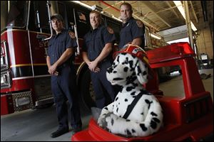 Brad Mauk, left, Shane Hillard, and Chris Wedge gather around Sparky, the mechanical fire dog, at Fire Station No. 4. Firefighters will visit Sylvania schools during National Fire Prevention Week, Oct. 7-13.