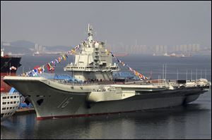 China's as yet unnamed aircraft carrier is decorated with colored flags at a shipyard in Dalian in northeast China's Liaoning province Monday.