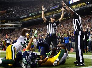 Officials signal after Seattle Seahawks wide receiver Golden Tate pulled in a last-second pass for a touchdown from quarterback Russell Wilson to defeat the Green Bay Packers 14-12 Monday.