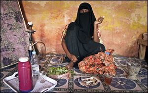 Prostitute Faduma Ali, who longs for the days when her pirate customers had money, chews the stimulant khat and smokes a cigarette at a house in the once-bustling pirate town of Galkayo, Somalia.