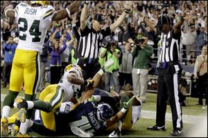 An official, rear center, signals for a touchdown by Seattle Seahawks wide receiver Golden Tate, obscured, as another official, at right, signals a touchback, on the controversial last play of an NFL football game against the Green Bay Packers in Seattle. The Seahawks won 14-12.
