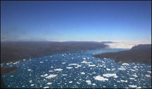 Icebergs and pieces of icebergs cover much of the water near the ice cap, visible in the background, in northern Greenland.