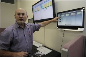 Jim Olzak, of Woodville, a founder of Nextronex, Inc., points to monitors for the solar panels at Bryan, Napoleon, and Collins Park in Toledo.