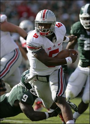 Ohio State quarterback Braxton Miller (5) avoids a tackle attempt by Michigan State safety Isaiah Lewis (9).