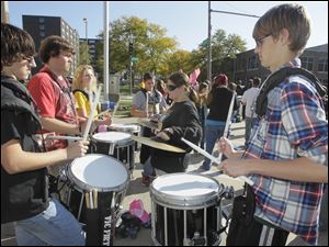 Clockwise, from left: Matt Phillips, a sophomore, seniors Brad Eisenmann and Liz Feltz, sophomore Nick Bartlett [fourth from left and facing camera], sophomore Christina Howard on the cymbals, and Garrett Weddington, a sophomore, of the Northview High School Marching Band, keep the beat for their bandmates and marchers at the event. 