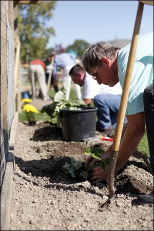 John Arnold, a parishioner of the All Saints Catholic Parish and School, participates in the first planting ceremony of the church's new garden.