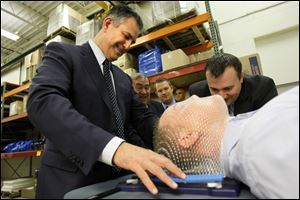 Francisco Sanchez, undersecretary for international trade at the U.S. Department of Commerce, tests out an embrace thermal plastic mask on Andrew Milanoski, a regional account manager at Bionix Development Corp. The thermoplastic mask is used for the treatment of brain cancer.