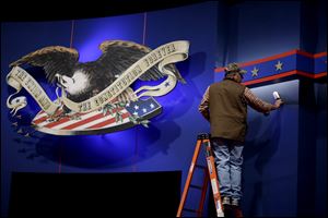 A worker cleans lint from the backdrop of the stage ahead of the first presidential debate. President Obama and GOP challenger Mitt Romney will go head to head for the first time today at the University of Denver. PBS veteran Jim Lehrer will moderate the debate, which is expected to focus on the economy.