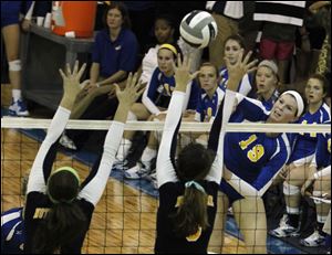 Notre Dame defenders jump to block a kill by St. Ursula's Maddie Burnham.